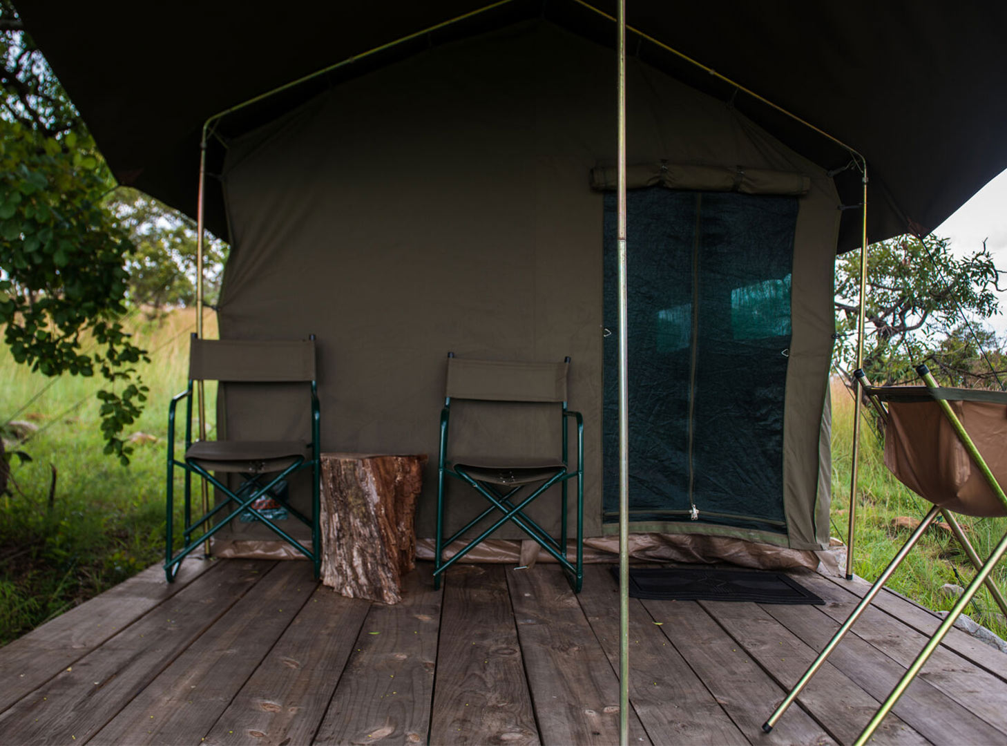 View of the Outside of a Tent with two camp chairs and wooden table on the deck