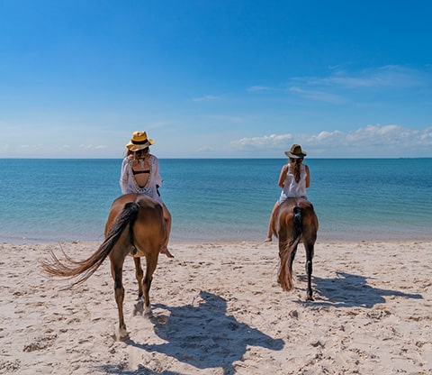 Two women riding horses on the beach in Bazaruto Archipelago National Park